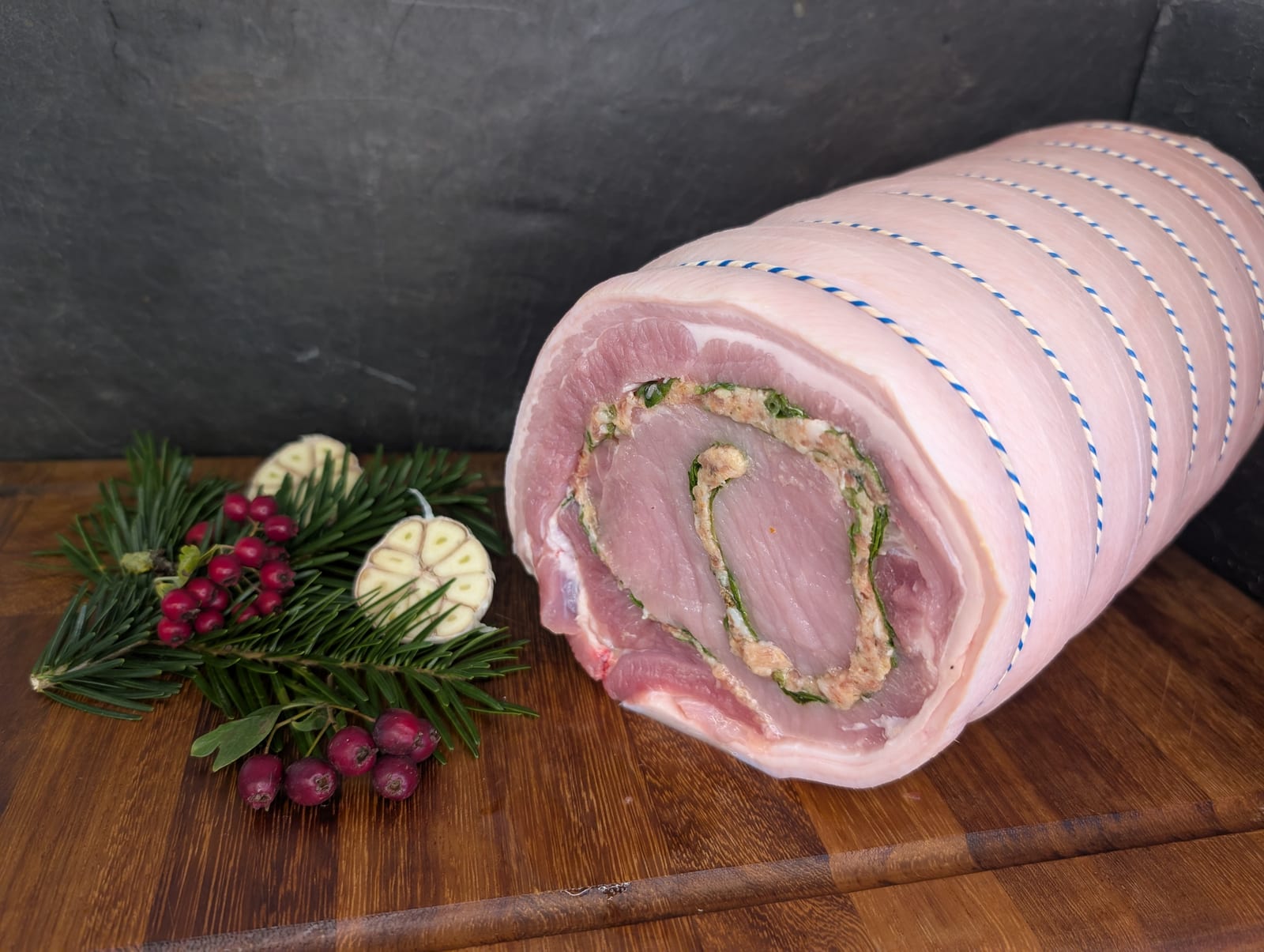 A stuffed, rolled pork joint on a slate board, ready to roast
